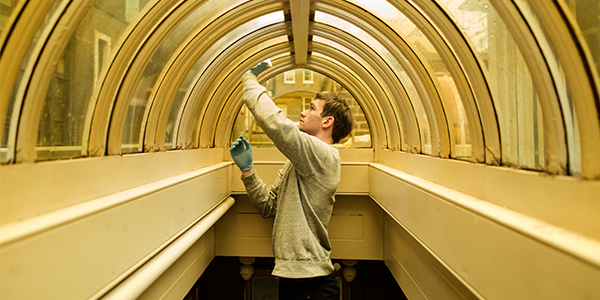 A conservator cleans a tinted lantern window high in Sir John Soane's Museum