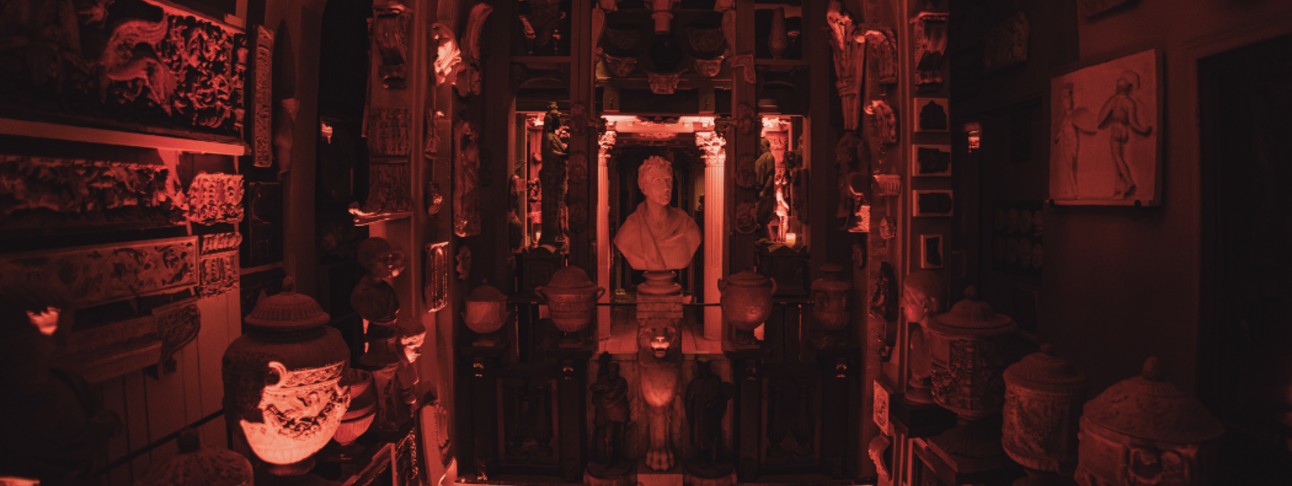 A photograph of the bust of Sir John Soane in the Dome, which is lit by orange uplighters.
