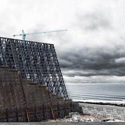 A digitally created image of a construction near a coast and a stormy sky