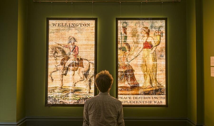 A visitor sits to observe the illuminated transparencies of Wellington and Peace, displayed in the Museum's Foyle Space.