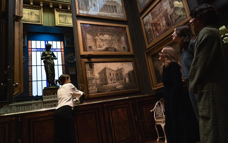 Visitors watch on as a Visitor Assistant opens the planes of the Picture Room to reveal the recess within, home to a statue of a nymph.