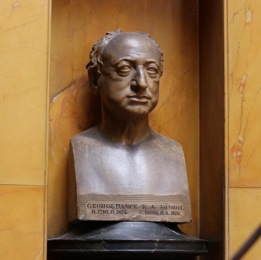 A sculptural bust of George Dance the Younger, in his old age, positioned in an alcove on the stairwell of Sir John Soane's Museum.