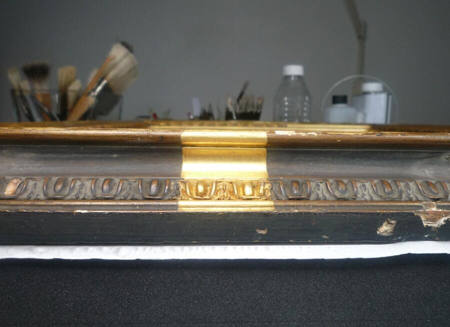 A section of cleaned frame, revealing the detail of the design and the brightness of the golden gilding.