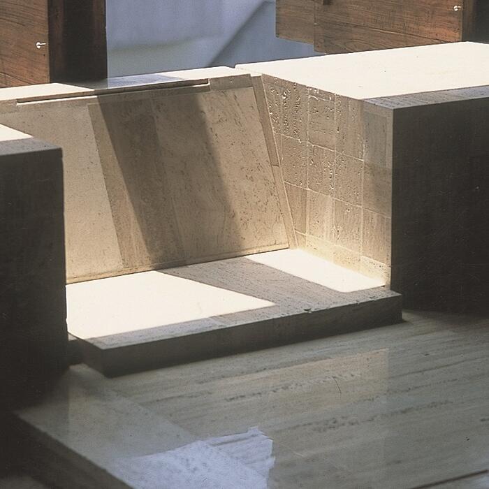 A sunken stone seating area in an apartment building, with sunlight streaming in.