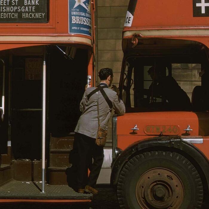 Two red London buses with a ticket inspector and bus driver talking