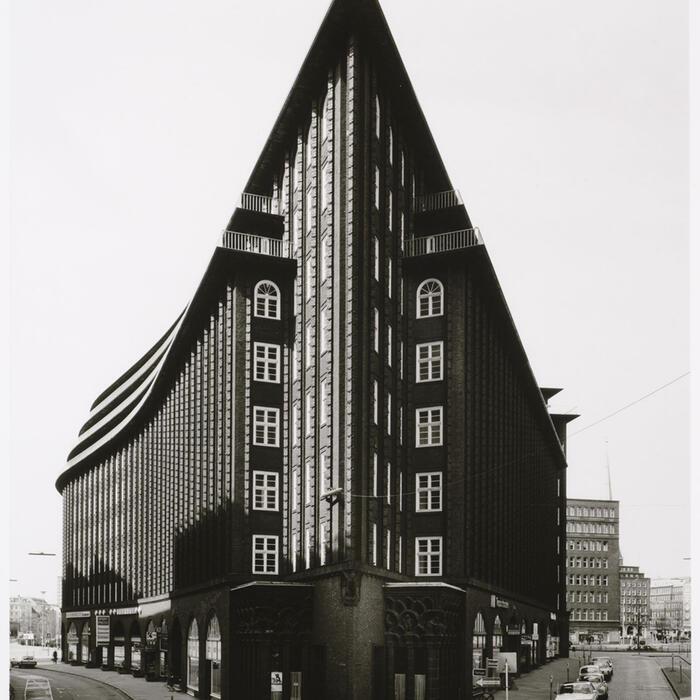 Striking black and white image of a building, with the angle exaggerating the corner, making it seem to cut into the sky