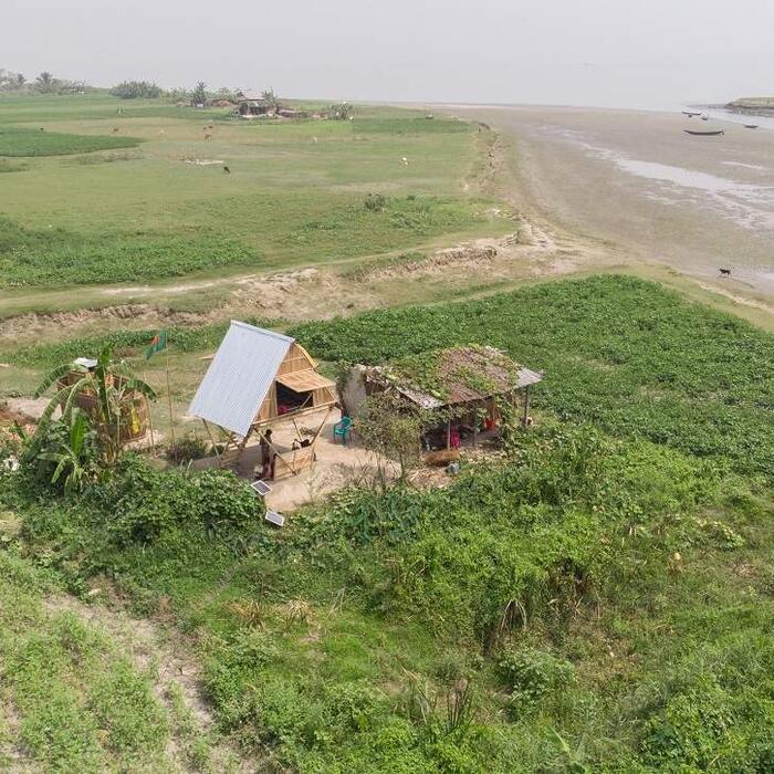 A photo of a modular mobile house in rural Bangladesh, next to a river.