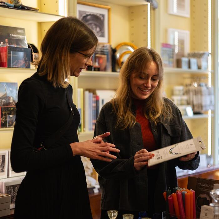 Two Museum visitors examine a pamphlet of architectural drawings in the Soane's shop.