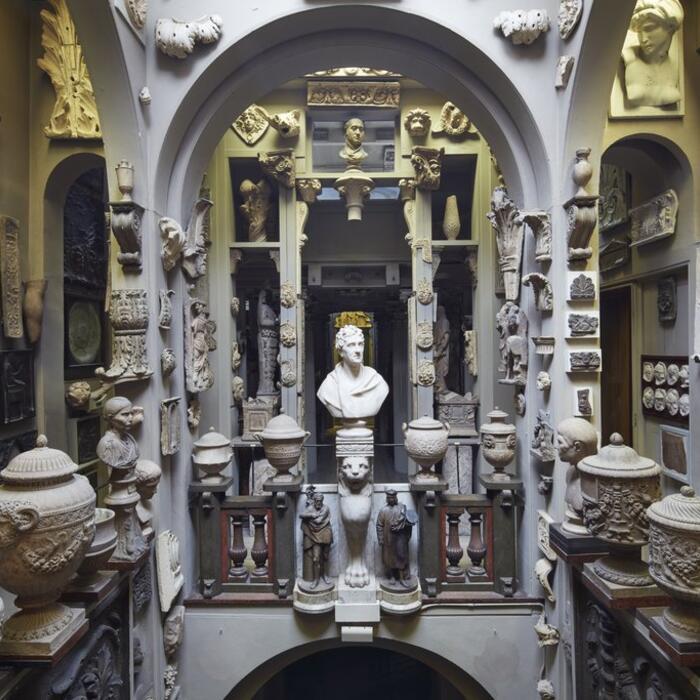 A room filled to the brim with plaster casts from ancient monuments, urns, and statue busts all placed around a central void