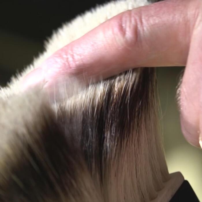 a finger brushing through a fine-haired brush