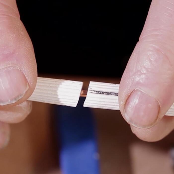 Hands sliding two pieces of plaster moulded as columns together along a thin metal pole