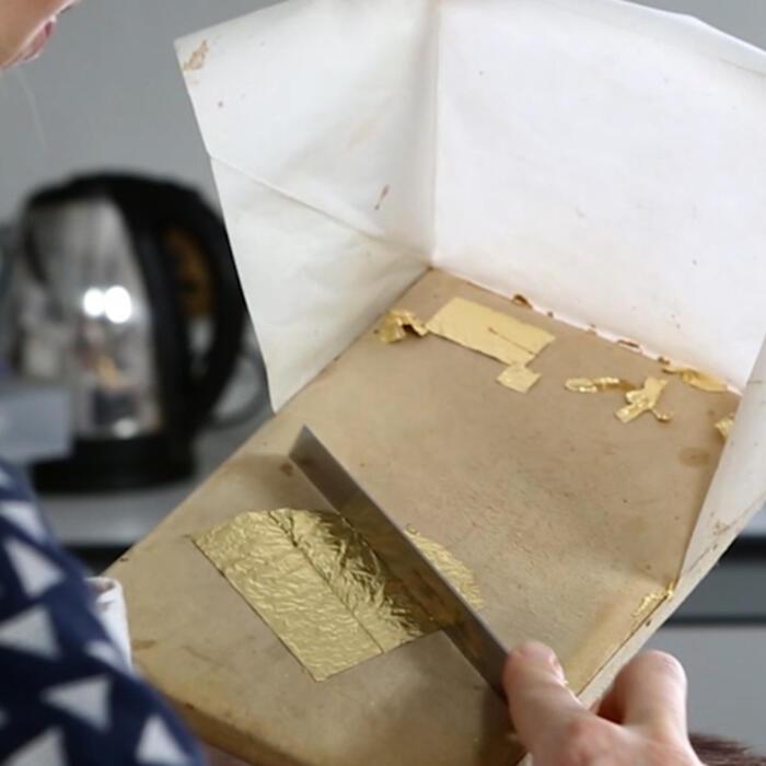 A conservator cutting gold leaf into small segments