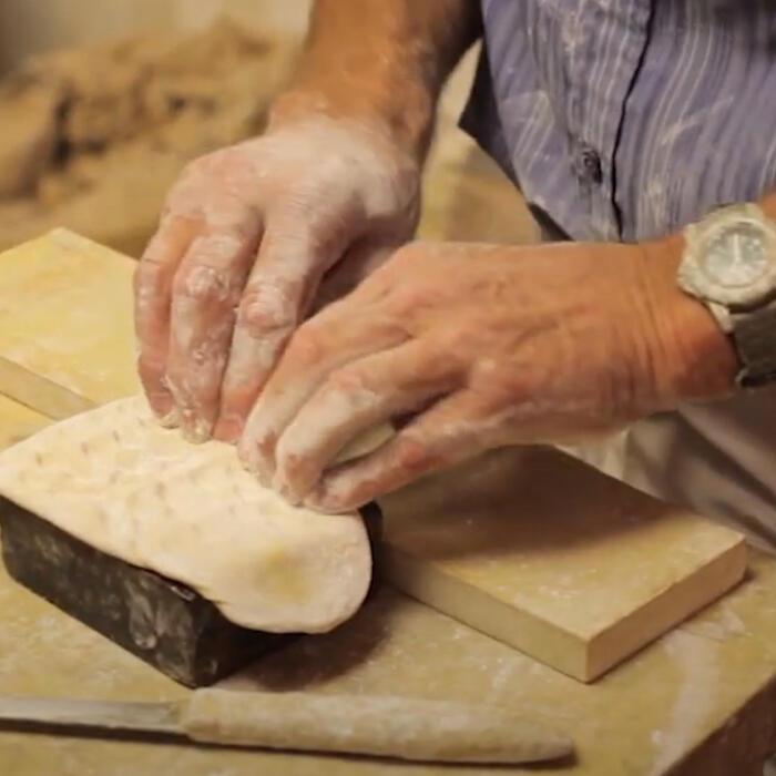 A person using their hands to push a plaster 'composition' into a wooden mould