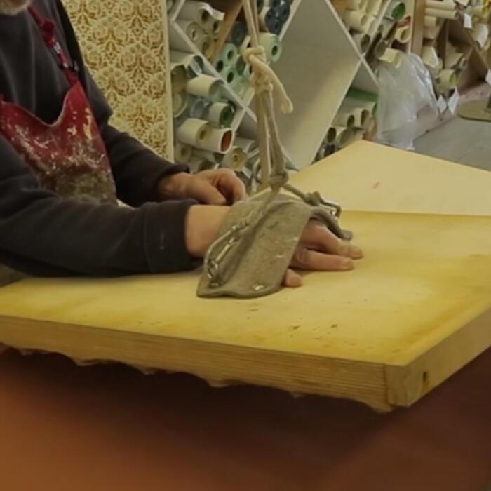 Hand printing the wallpaper, involving lowering a huge wooden block onto the paper painted with the red background
