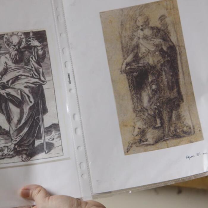 Printouts of 17th century sketches of the missing window panels, being examined by a restorer