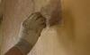 The hand of a conservator working on a patch of the Private Apartments' wall. The original paper is showing through the later paint