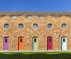 An undulating terrace of small residences with brightly coloured doors.
