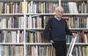 Kenneth Frampton, recipient of the 2019 Soane Medal, standing on a ladder in front of a row of bookshelves