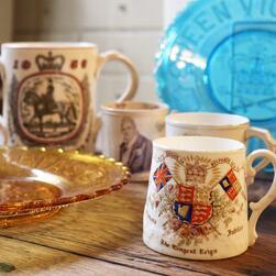 A selection of royal memorabilia mugs and plates. In the foreground, a mug bearing the royal crest celebrates Queen Victoria's diamond jubilee.