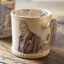 A William IV and Queen Adelaide mug celebrating their coronation in 1831, bearing his portrait.