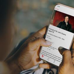 Hands holding a phone displaying information about a painting of Sir John Soane