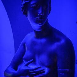 A plaster cast of Venus di Medici, bathed in blue light.