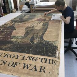 A conservator cleans the transparency featuring the figure of peace.