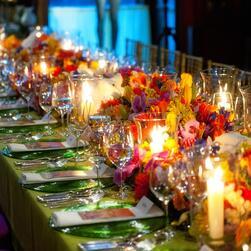 Orange and pink flowers with tealights on a green tablecloth