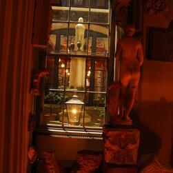 A classical statue of a female figure, illuminated by low warm light, stands facing out into the illuminated courtyard at the heart of the Museum.