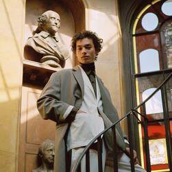 A man in a suit on a staircase in front of a bust of a man