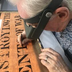 A conservator infills holes in the illumination.