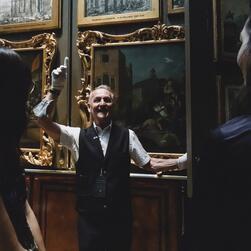 A member of the Museum team opens the panels of the Picture Room for visitors to look within.
