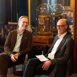 Will Gompertz sits to the right of Martin Brudnizki, both smiling.