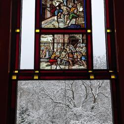 A view of some snow covered trees from a stained glass window