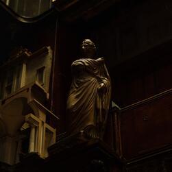 A dramatic classical figure looms over the viewer in the gloom of the Monk's Parlour.