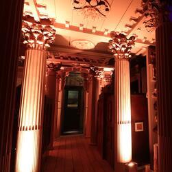 The Colonnade, with its pillars warmly lit by uplighters, facing the closed door of the Picture Room. The Canaletto is visible through the window.